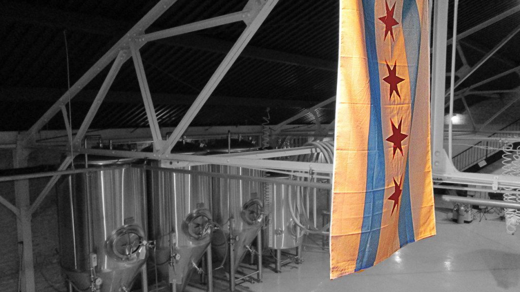 The Chicago flag hangs in front of beer fermenters as part of our list of the best breweries in Chicago.